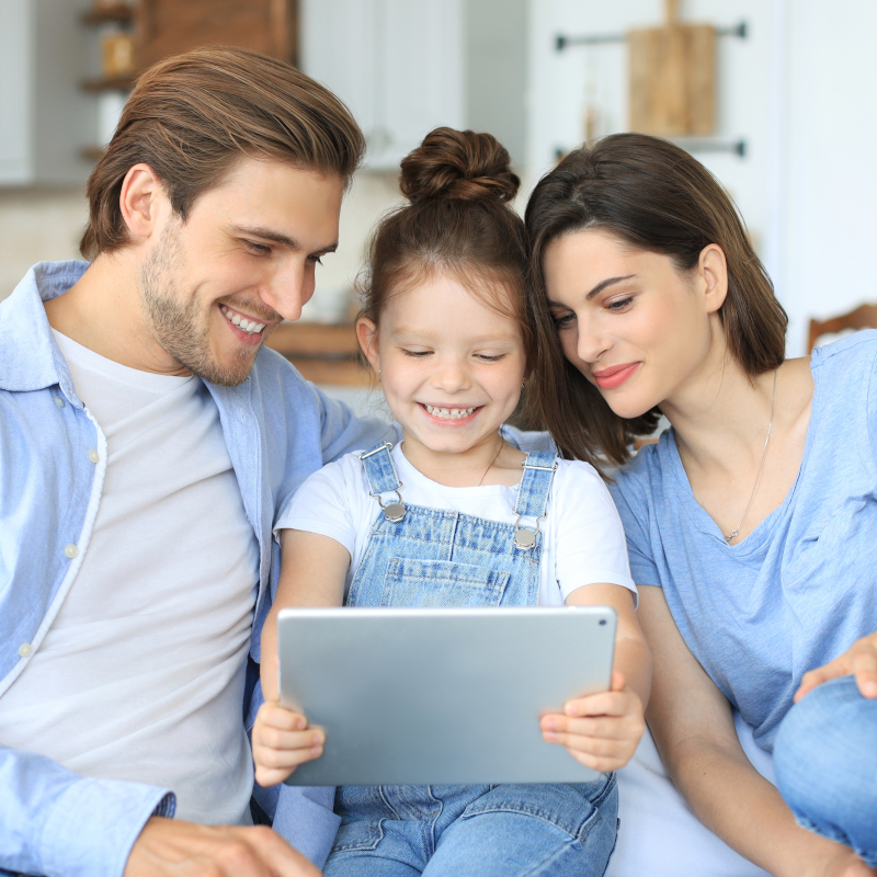 Young parents and their daughter answering a video call on a digital tablet
